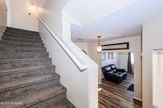 stairway with wood finished floors, visible vents, and baseboards