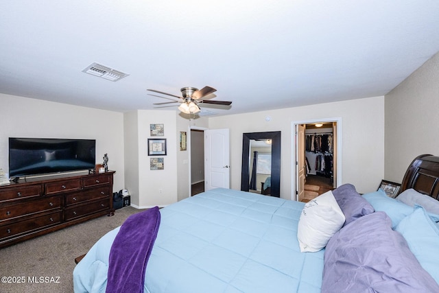 bedroom with a walk in closet, carpet, visible vents, and a ceiling fan