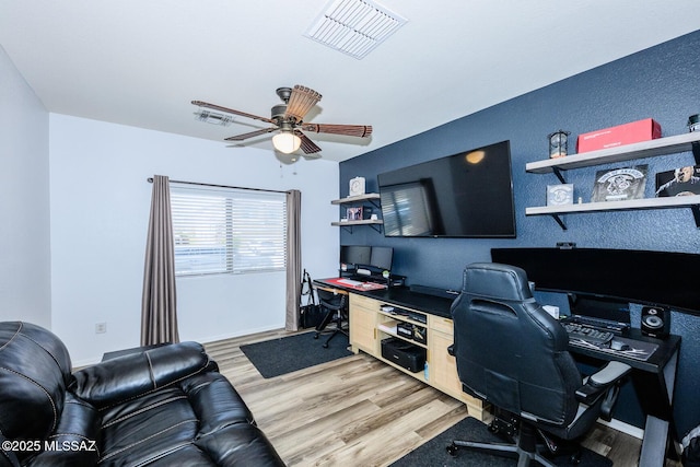 office space featuring light wood finished floors, visible vents, baseboards, and a ceiling fan