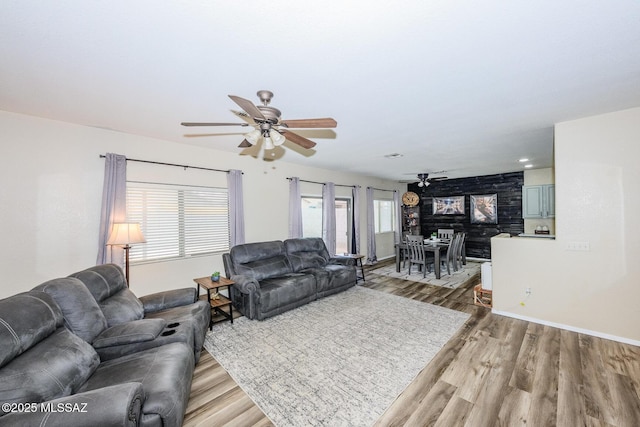 living room featuring baseboards, light wood-style floors, and a ceiling fan