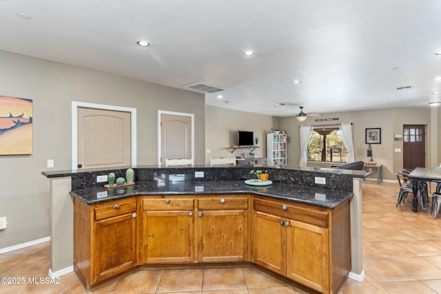 kitchen featuring open floor plan, visible vents, dark stone countertops, and a ceiling fan