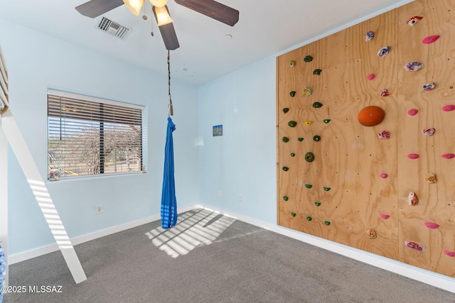 carpeted empty room with visible vents, baseboards, and ceiling fan