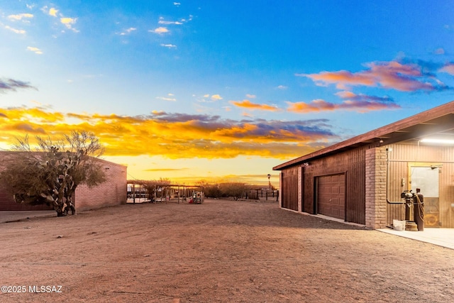 yard at dusk with a garage and an outdoor structure