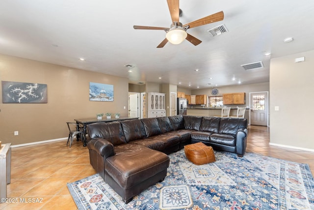 living room with light tile patterned floors, visible vents, baseboards, and a ceiling fan