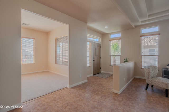 living room featuring visible vents, plenty of natural light, baseboards, and a tray ceiling