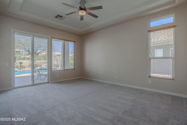 tiled dining space featuring a ceiling fan, a tray ceiling, visible vents, and a healthy amount of sunlight