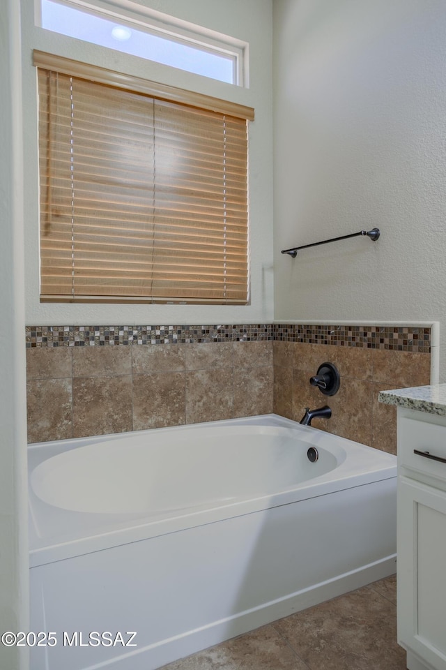 full bath with double vanity, a bath, a ceiling fan, and a sink