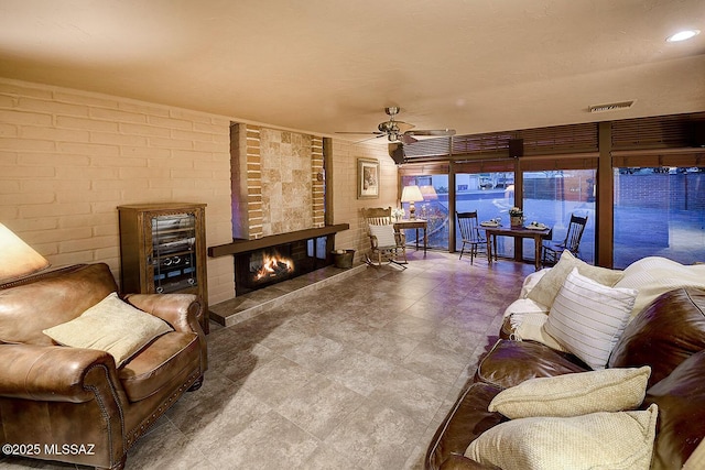 living room featuring a brick fireplace, brick wall, and a ceiling fan