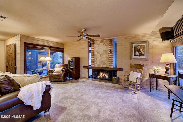 living area with a fireplace, a textured ceiling, and ceiling fan