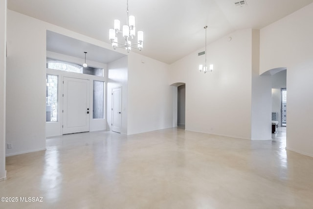 foyer entrance with arched walkways, high vaulted ceiling, concrete floors, and an inviting chandelier