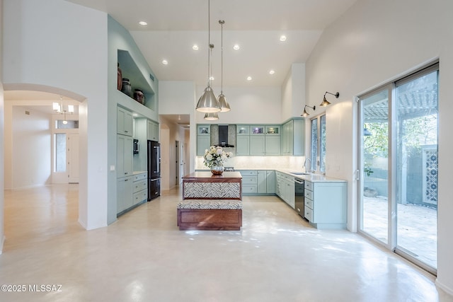 kitchen with finished concrete flooring, arched walkways, wall chimney exhaust hood, green cabinetry, and a towering ceiling