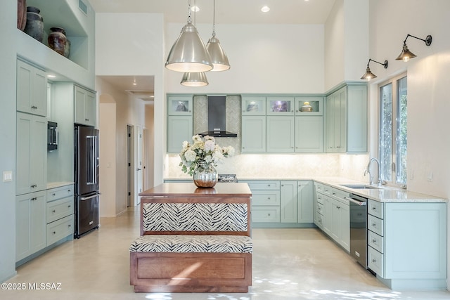 kitchen with backsplash, stainless steel appliances, wall chimney range hood, and a towering ceiling