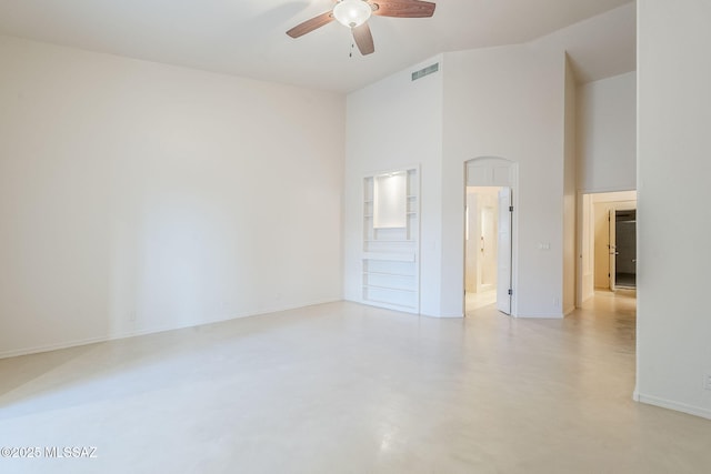 interior space featuring visible vents, baseboards, ceiling fan, finished concrete floors, and a high ceiling