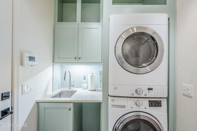 laundry area with stacked washer / dryer, cabinet space, and a sink