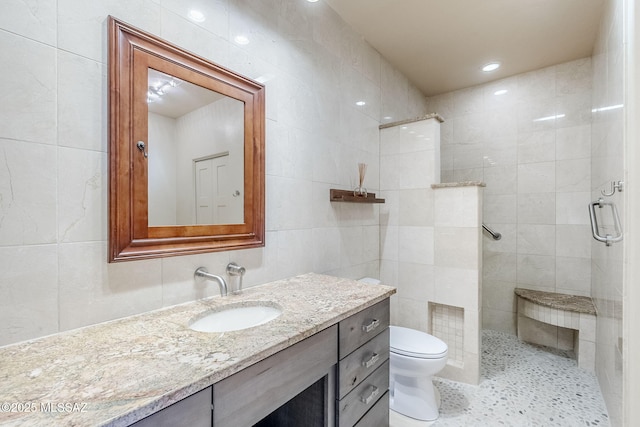 full bath featuring toilet, tile walls, a stall shower, and vanity