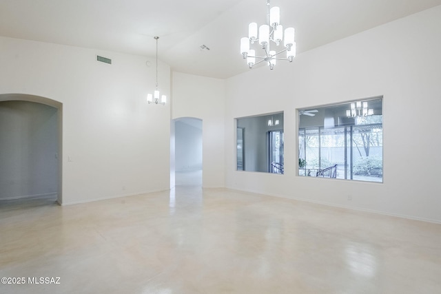 empty room with arched walkways, a notable chandelier, and finished concrete flooring