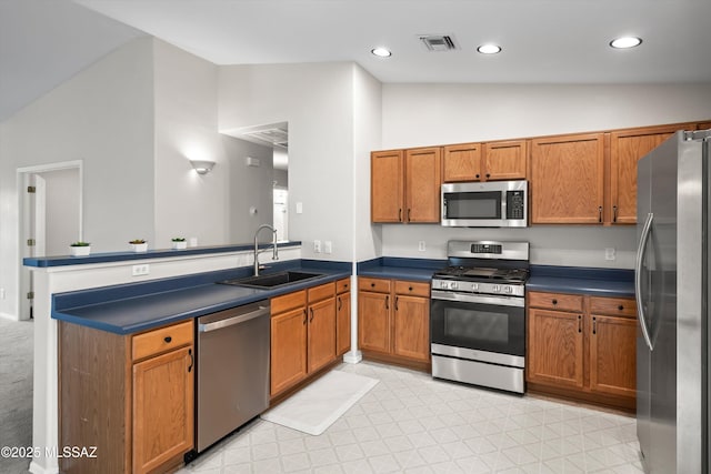 kitchen with visible vents, vaulted ceiling, a peninsula, stainless steel appliances, and a sink