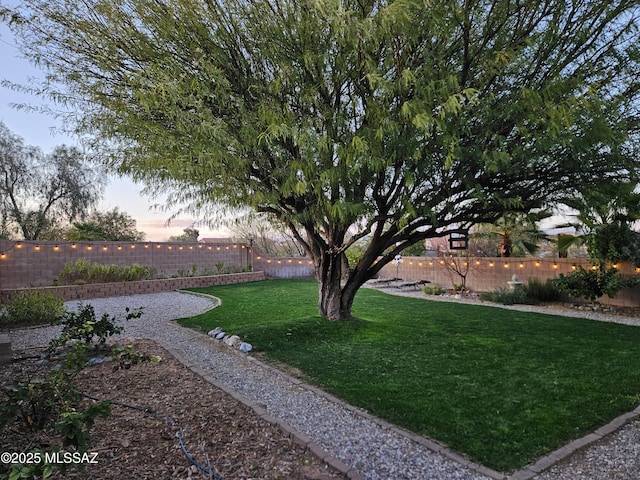 yard at dusk featuring a fenced backyard