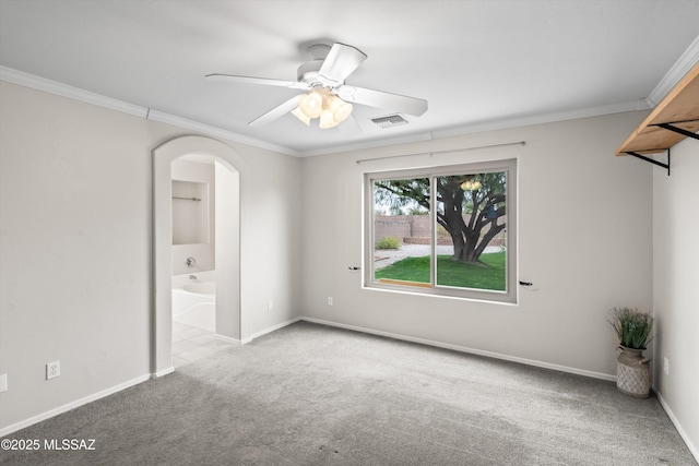 carpeted spare room featuring visible vents, baseboards, ceiling fan, and ornamental molding