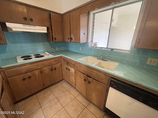 kitchen featuring white appliances, tile countertops, a sink, under cabinet range hood, and tasteful backsplash