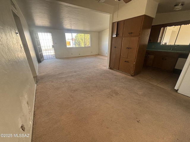 unfurnished living room with light colored carpet and ceiling fan