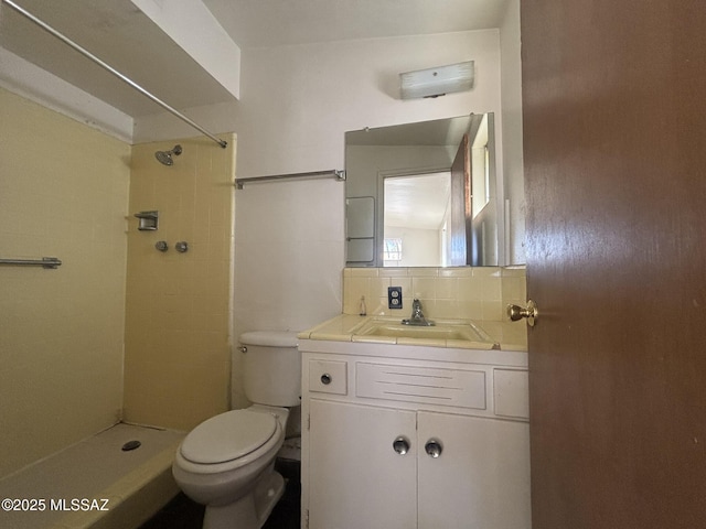 full bathroom with vanity, toilet, backsplash, and tiled shower