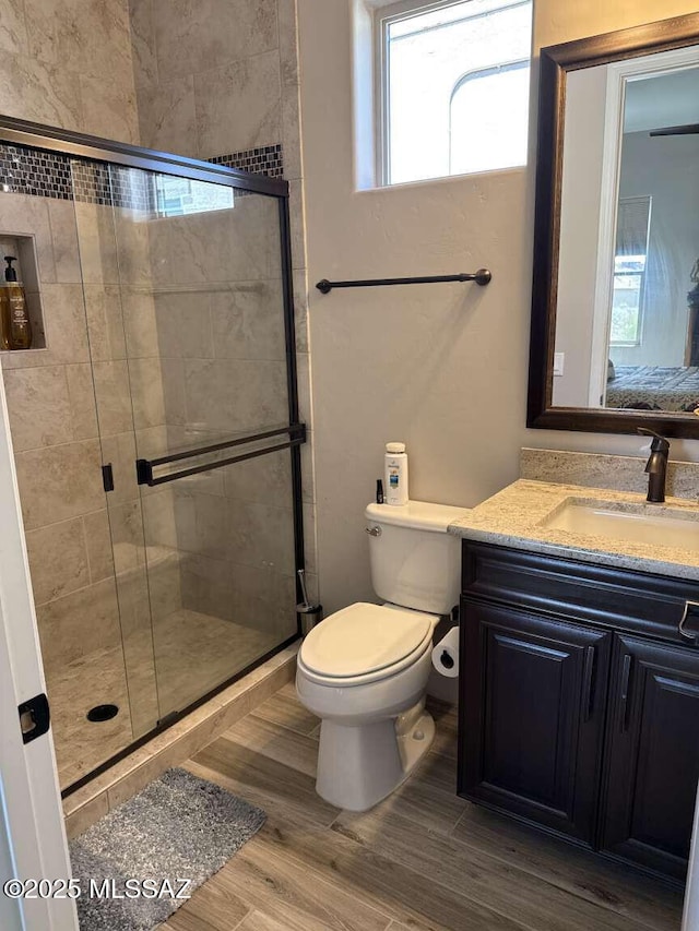 full bath featuring vanity, a shower stall, toilet, and wood finished floors