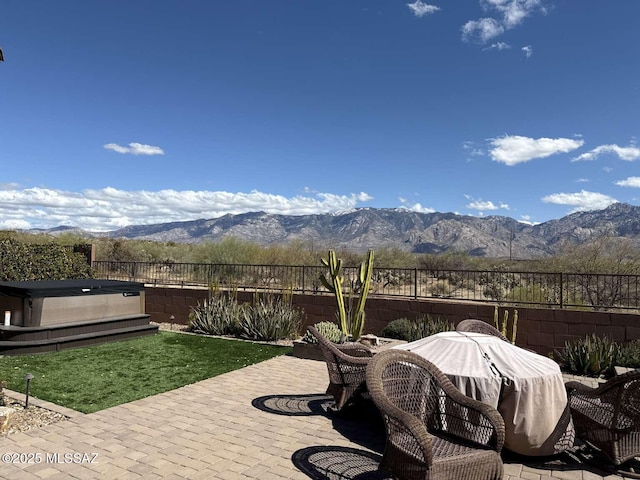 exterior space featuring a mountain view, a hot tub, and a fenced backyard