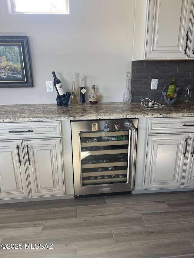 bar with tasteful backsplash, beverage cooler, wood tiled floor, and a dry bar