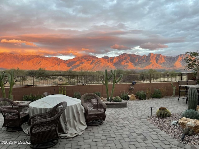 patio terrace at dusk featuring a mountain view and fence