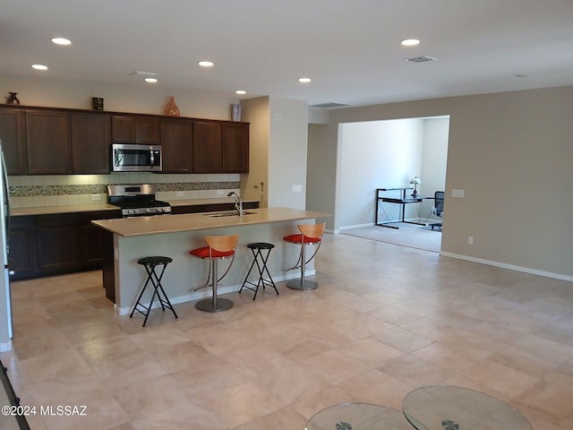 kitchen with backsplash, appliances with stainless steel finishes, a breakfast bar area, and a kitchen island with sink