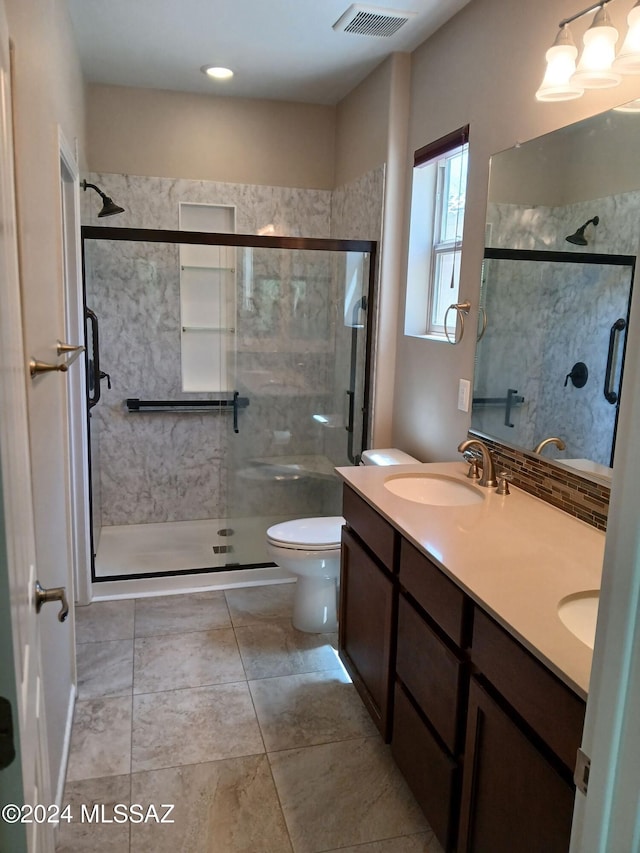 bathroom with visible vents, toilet, a stall shower, a sink, and double vanity