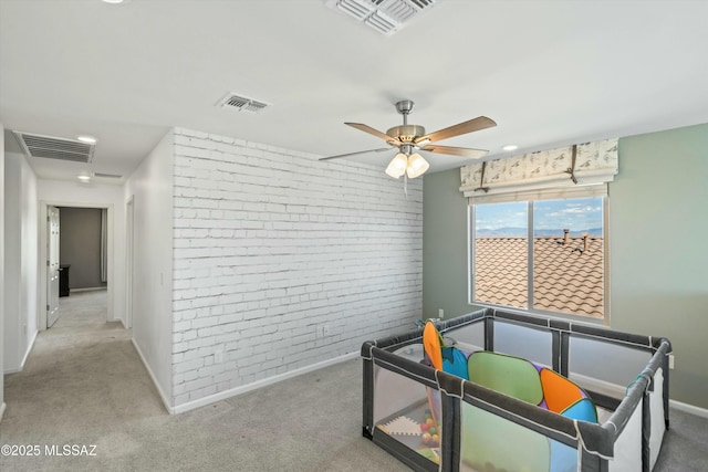 interior space with visible vents, brick wall, and a ceiling fan