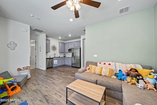 living area with recessed lighting, visible vents, wood finished floors, and a ceiling fan