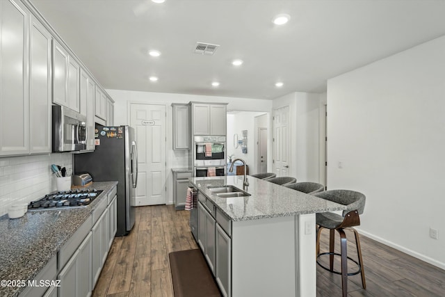 kitchen featuring a breakfast bar area, dark wood-style floors, visible vents, a sink, and stainless steel appliances