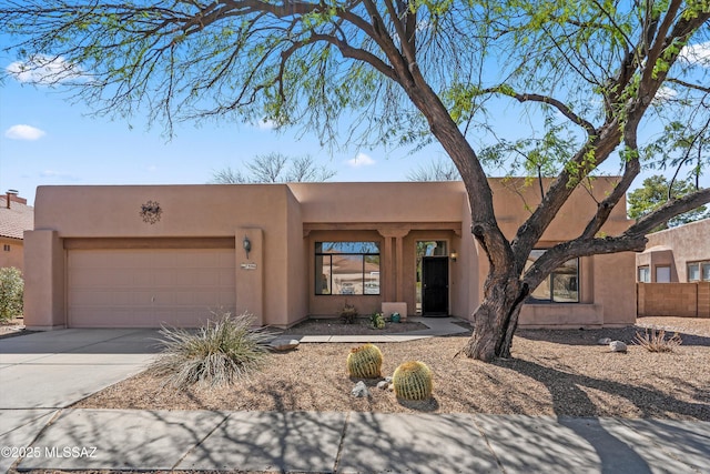 pueblo-style home featuring stucco siding, concrete driveway, and a garage