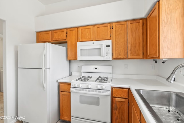 kitchen with a sink, white appliances, brown cabinets, and light countertops