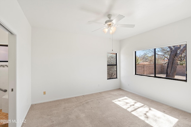 empty room with carpet flooring, a ceiling fan, and baseboards