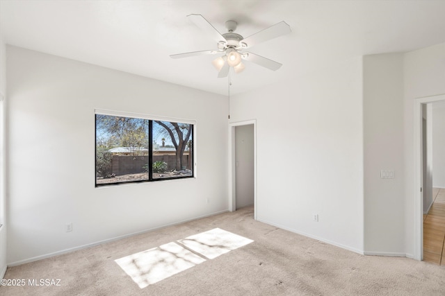 empty room with light colored carpet, baseboards, and ceiling fan