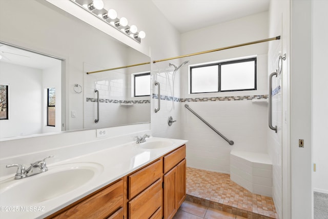 full bathroom featuring double vanity, a tile shower, and a sink