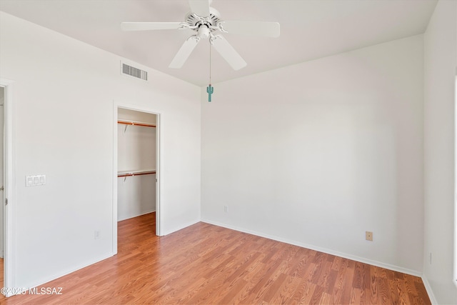 unfurnished bedroom featuring a spacious closet, visible vents, ceiling fan, light wood-style floors, and a closet