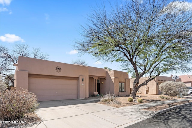 adobe home featuring concrete driveway, a garage, and stucco siding