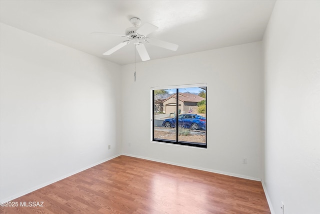 empty room with baseboards, wood finished floors, and a ceiling fan