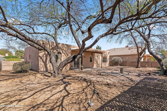 back of property featuring a patio area, stucco siding, a chimney, and fence