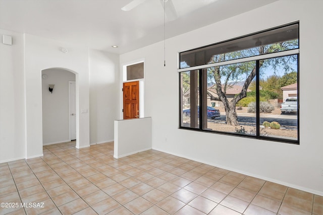 spare room featuring light tile patterned floors, a ceiling fan, baseboards, recessed lighting, and arched walkways