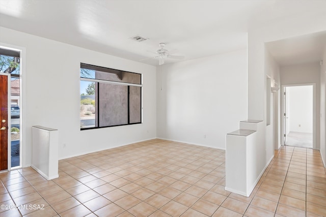 empty room with light tile patterned floors, visible vents, baseboards, and ceiling fan