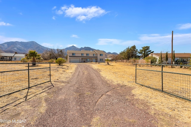 view of front of property with a mountain view, an attached garage, driveway, and fence