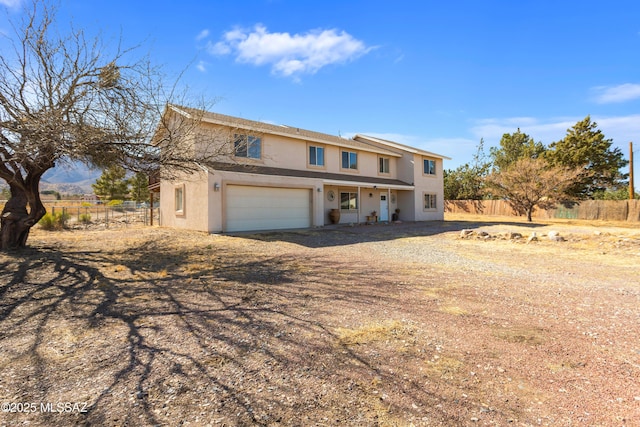 view of front of property featuring an attached garage, fence, and stucco siding