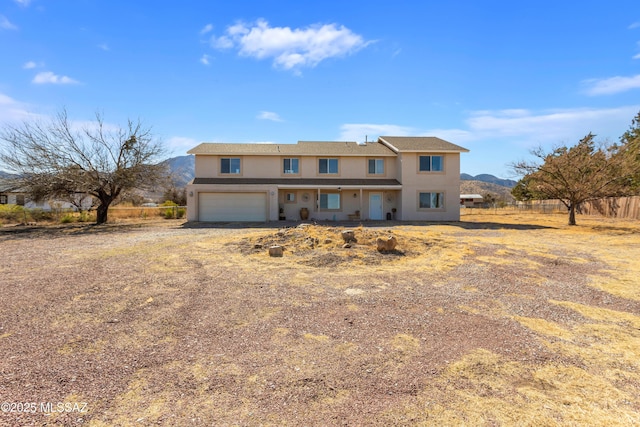 view of front of house with an attached garage, fence, driveway, and stucco siding