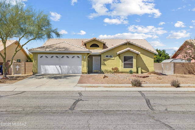 view of front of house featuring concrete driveway, a tile roof, a garage, and fence